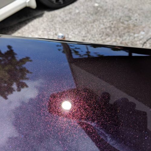 Glossy mirror finish on a dark purple car hood after paint correction